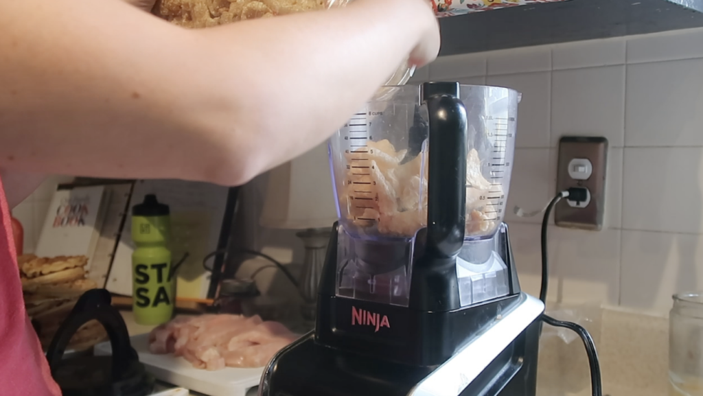 lady pouring pork rinds into a food processor