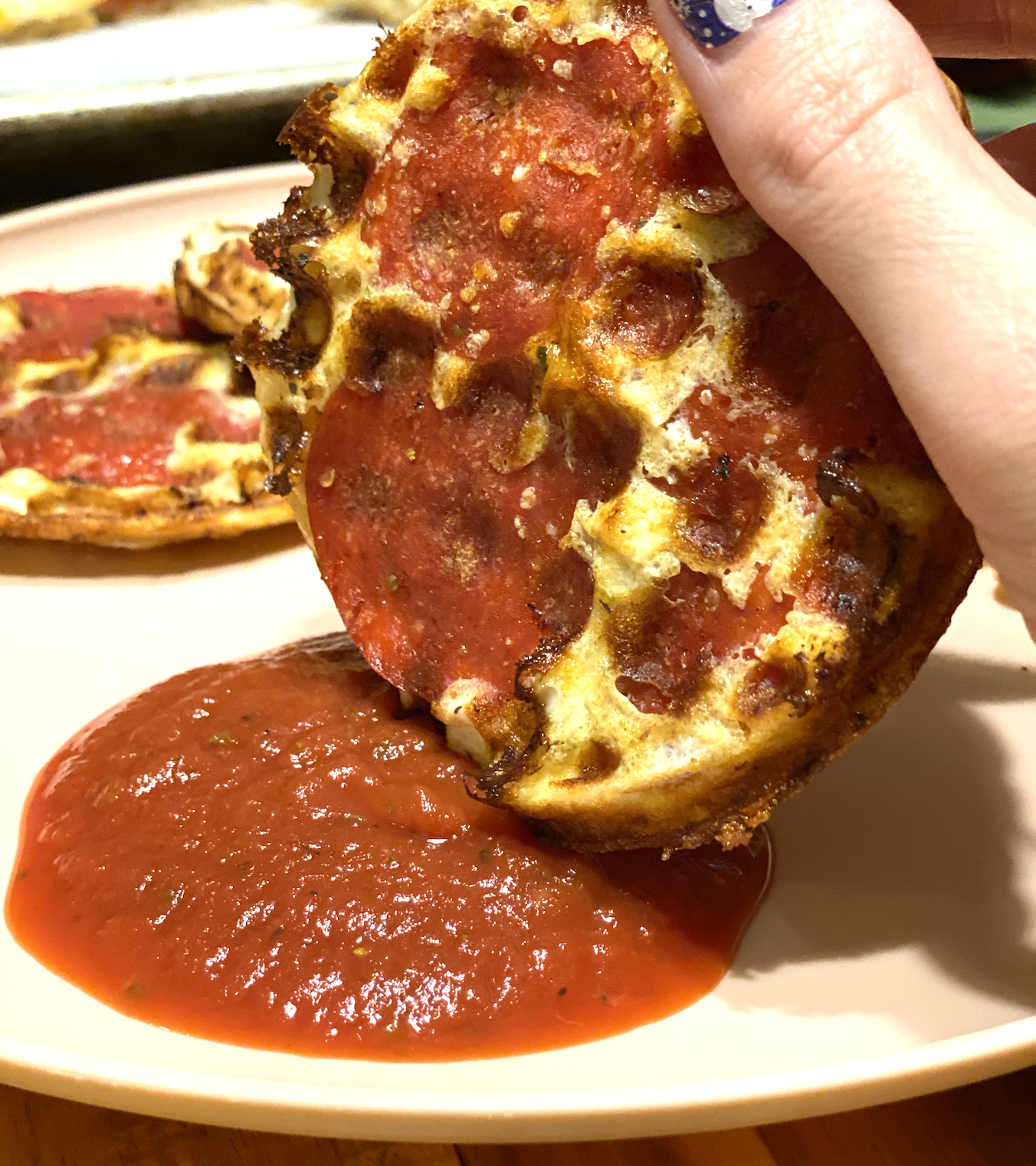 pizza chaffle being dipped in marinara sauce