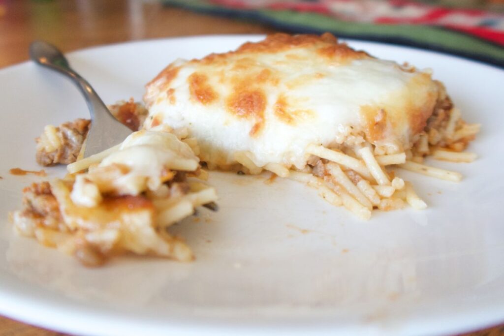 baked spaghetti on a white plate with a silver fork