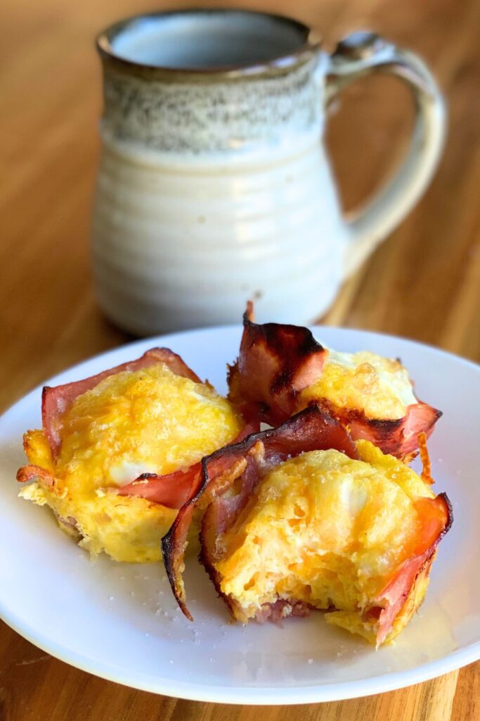 ham, egg and cheese cups on a white plate with a cup of coffee