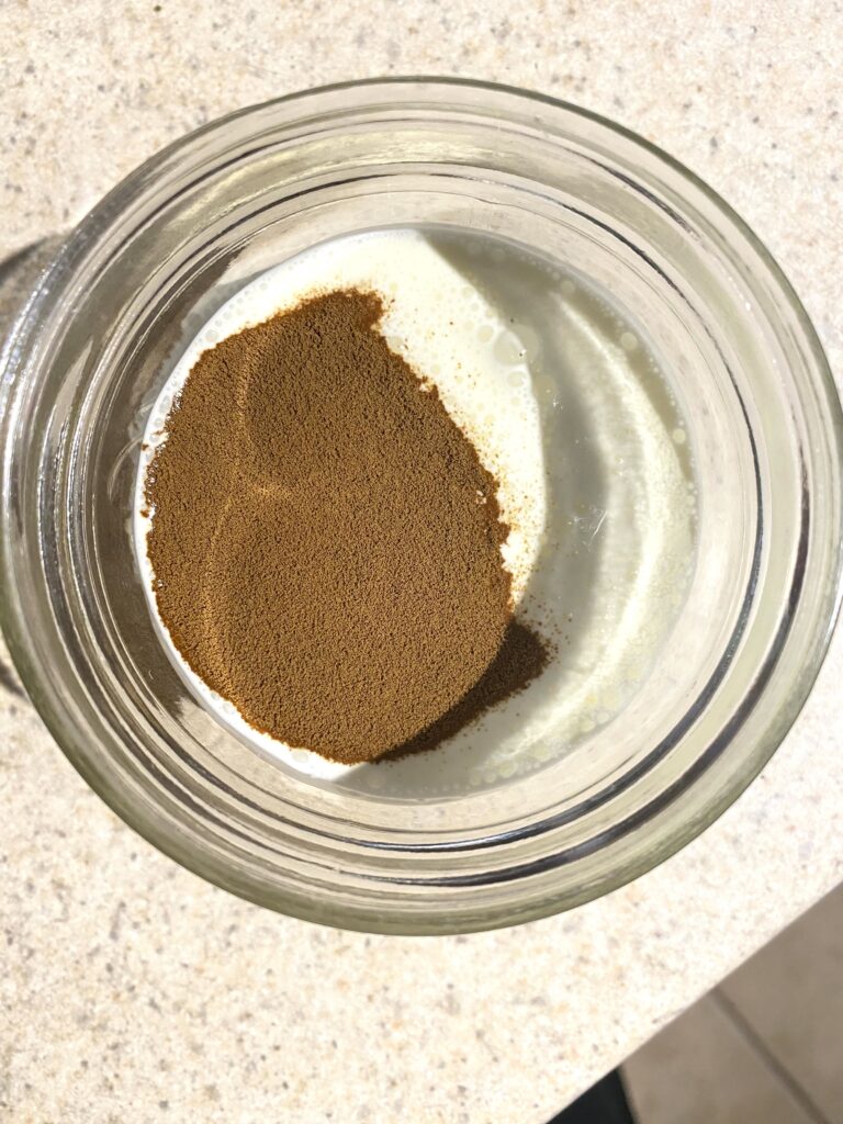 close up photo of heavy cream in a jar with a scoop of instant coffee on top