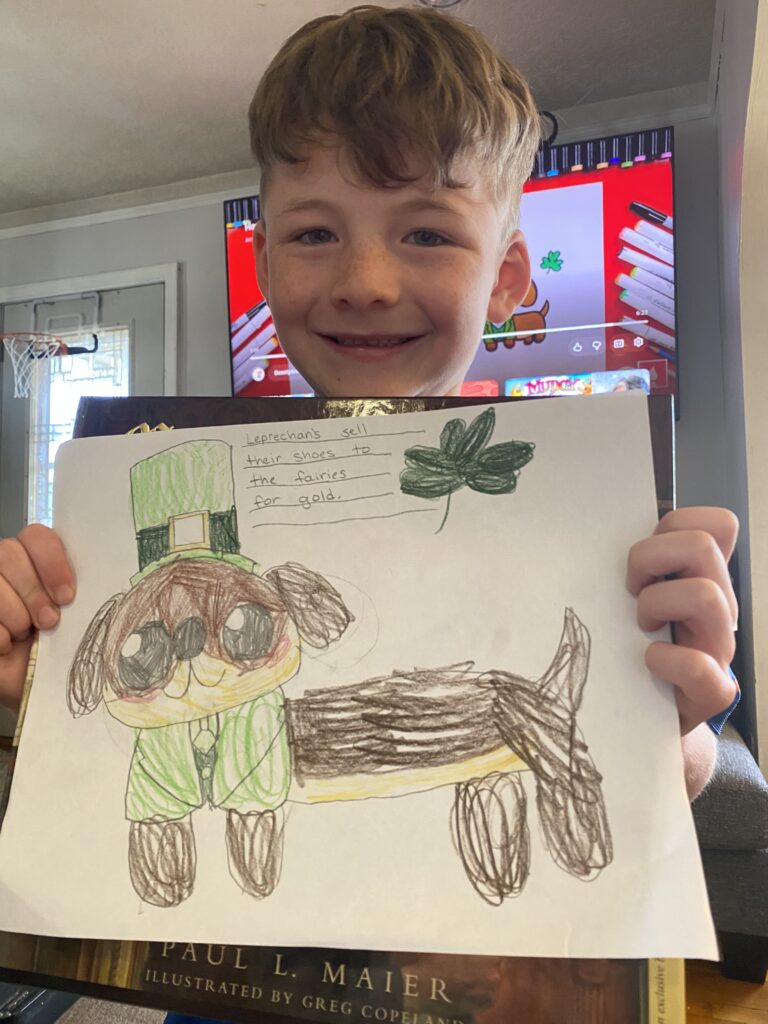 boy holding a drawing of a st. patricks day dauchsand.