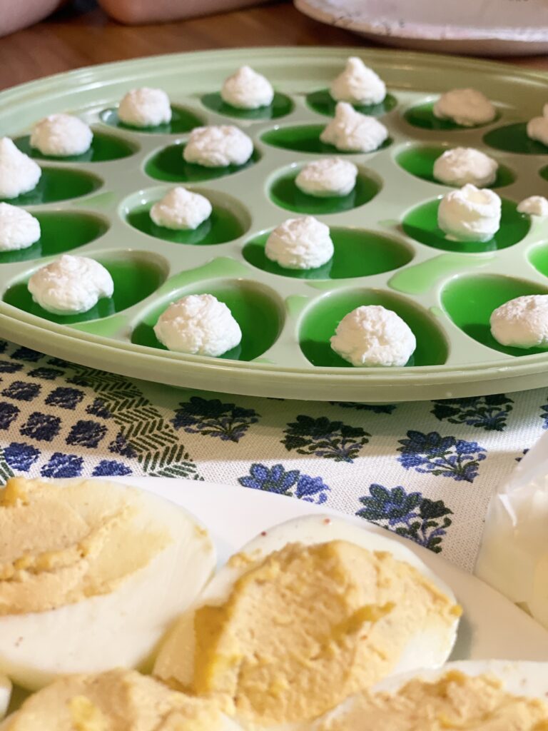 close up of green jello eggs with whipped cream on top and some deviled eggs.